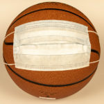 Protective mask on a basketball on a light background. The concept of sporting events during the COVID-19 pandemic